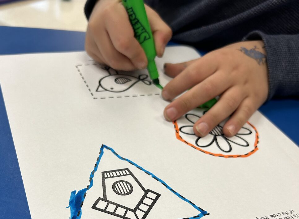 student completing a tracing worksheet with a scented marker