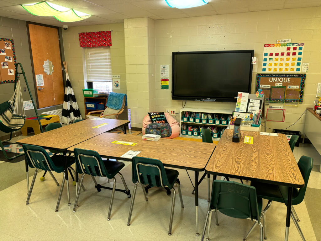 three rectangular tables are placed in a "U" shape to create space for students to sit together at the touchscreen board