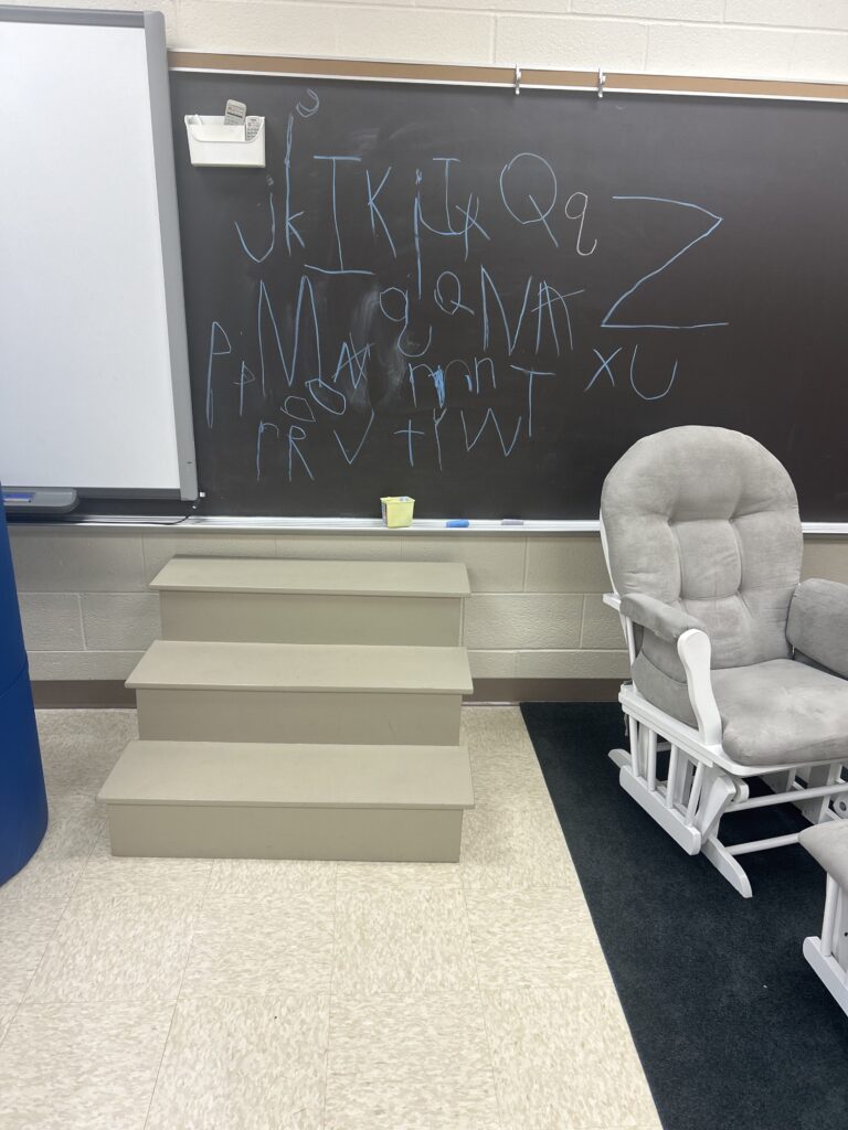 steps in from of and rocking chair next to the chalkboard with letters written on it in chalk