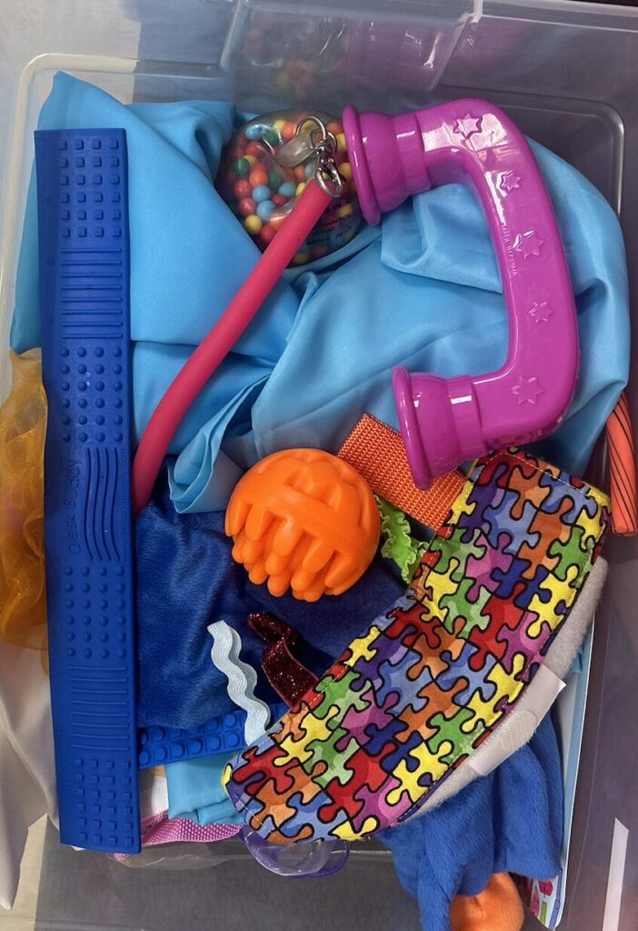 fidet bin with whisper phone, home made tactile fidget, Desk Buddy, stress balls, bell textured balls, sensory noodles, etc. 