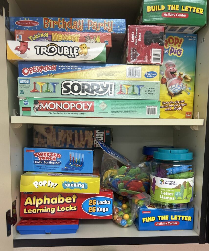 fine motor game closet with games like Pop It Spelling, Fine The Letter, Pop Beads, Lacing Cards, Pop the Pig, etc.