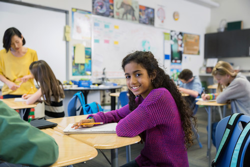 Student is smiling in the middle of her classroom during center time