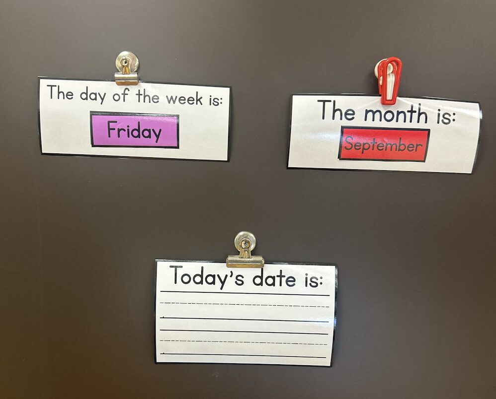 Morning Meeting resources clipped on the board - The day of the week is Friday and The month is September with a blank Today's date is piece