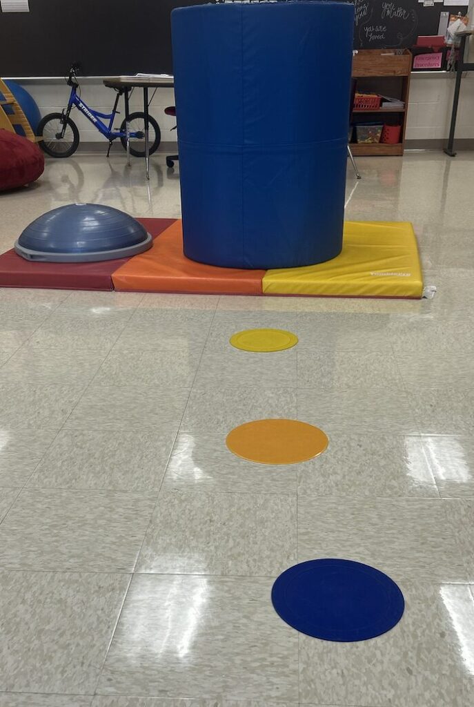 path of poly spots leading to a blue 3 foot barrel on a mat next to a bosu ball