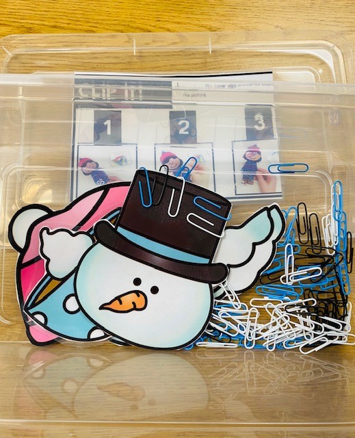 A fine motor "clip it" center, with a snowman head and assorted paper clips