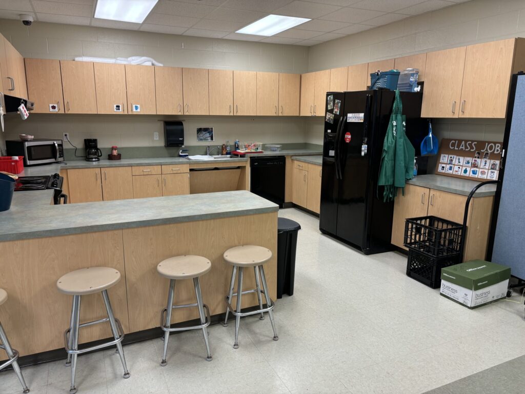 classroom kitchen is utilized for middle school life skills and includes normal kitchen appliances as well as visuals for instruction and communication