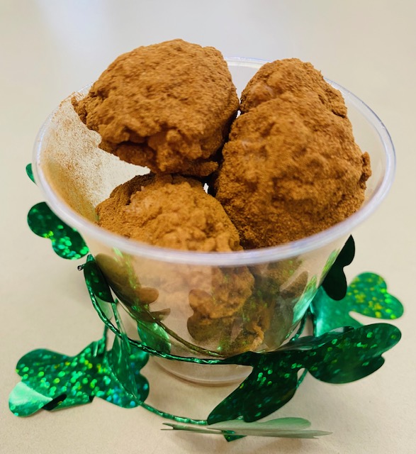A close-up picture of Irish Potato Candy in a cup. The candies are small potato-shaped balls covered in cinnamon.
