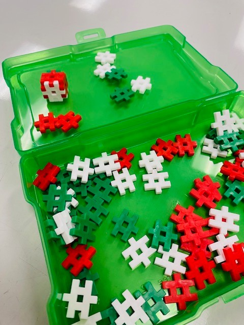 A green container filled with white, red, and green interlocking STEM building blocks.