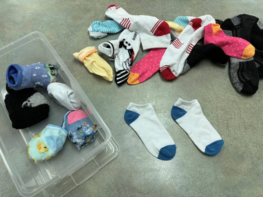mixed socks lay on a table so that students may work on pairing socks