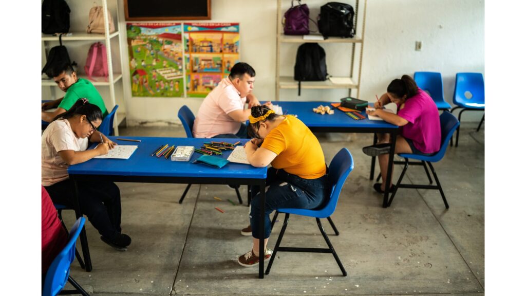 Image of a self-contained classroom featuring 5 students with disabilities sitting at their desks working.
