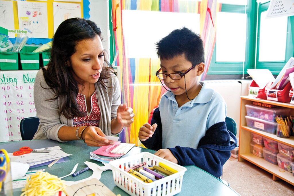 A teacher working one on one with a student on a craft
