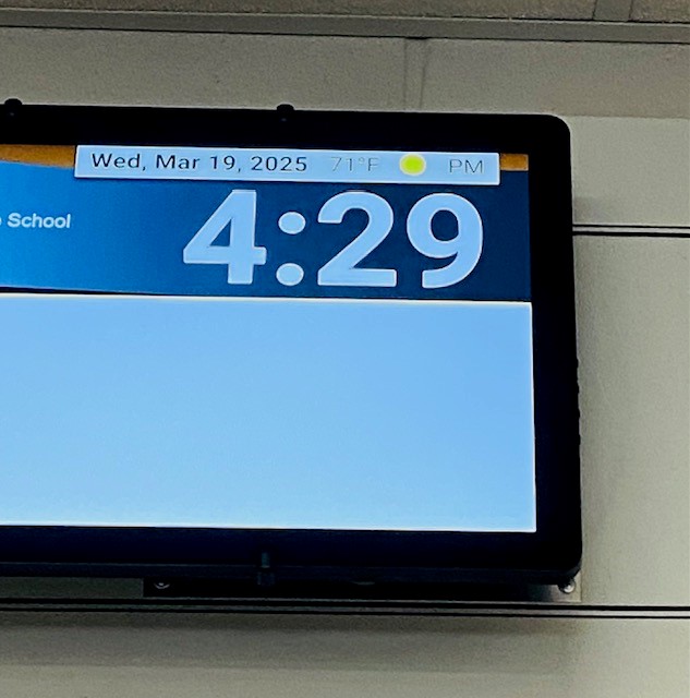 A digital clock screen on a classroom wall. The time reads 4:29.