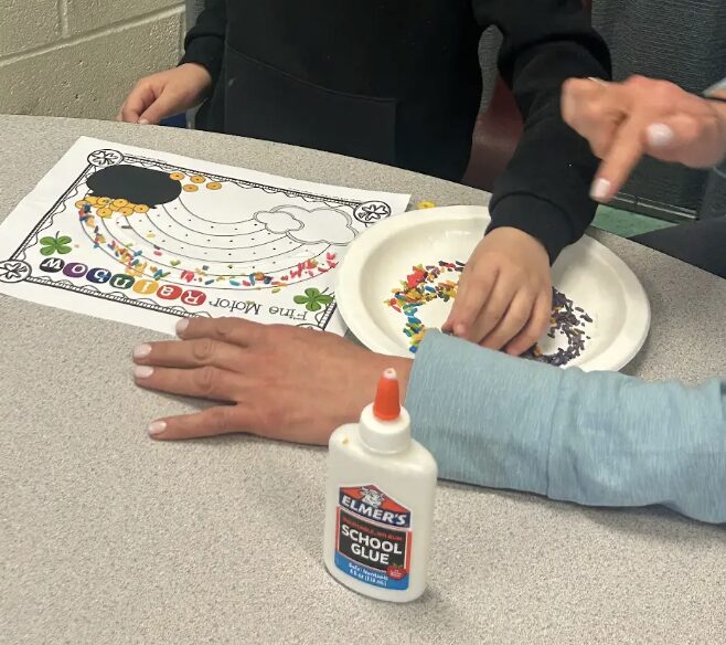 student completing a sensory craft with adult help