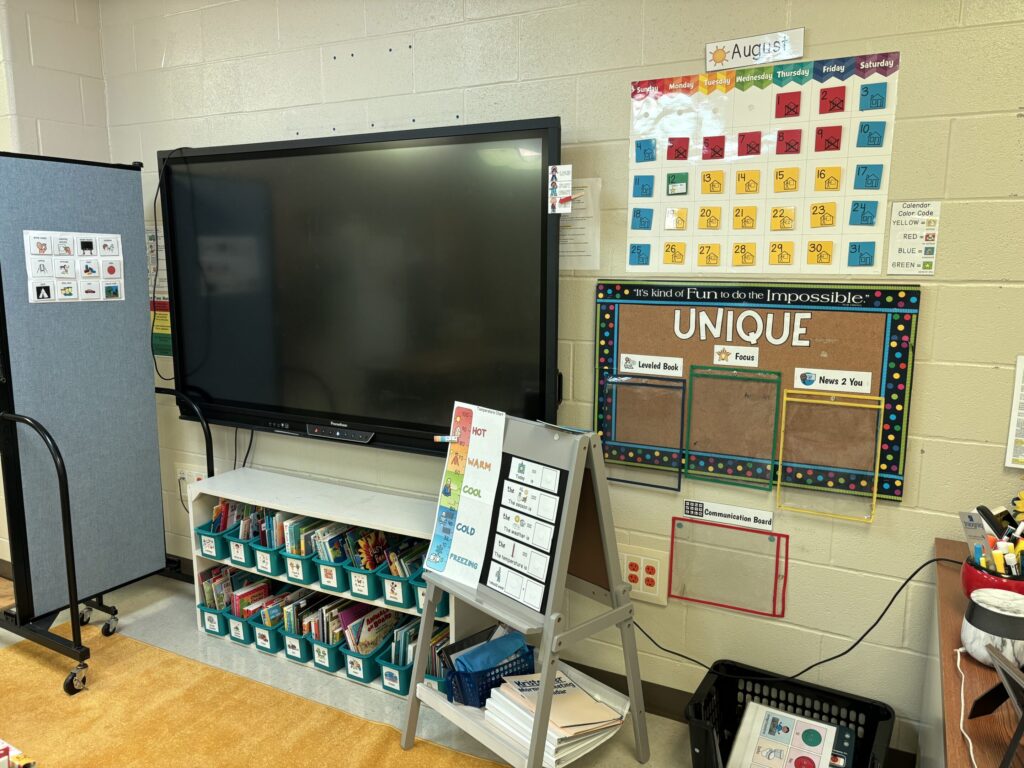 a touchscreen board is surrounded by a calendar, curriculum pieces, and other visuals for student success