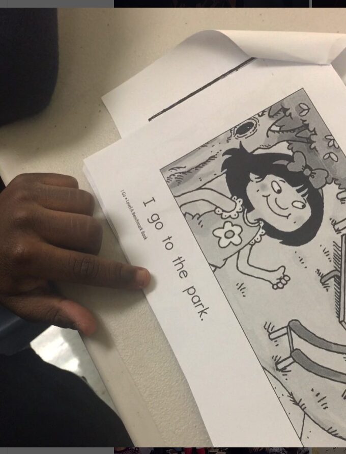 Child's hand pointing to words in a book