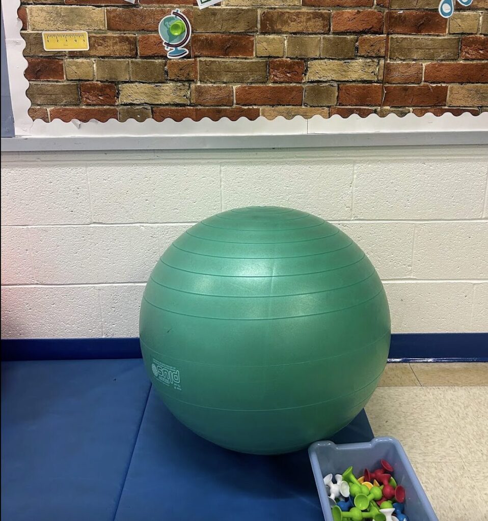 yoga ball with bin on squigs behind it facing a bulletin board wall with brick wallpaper