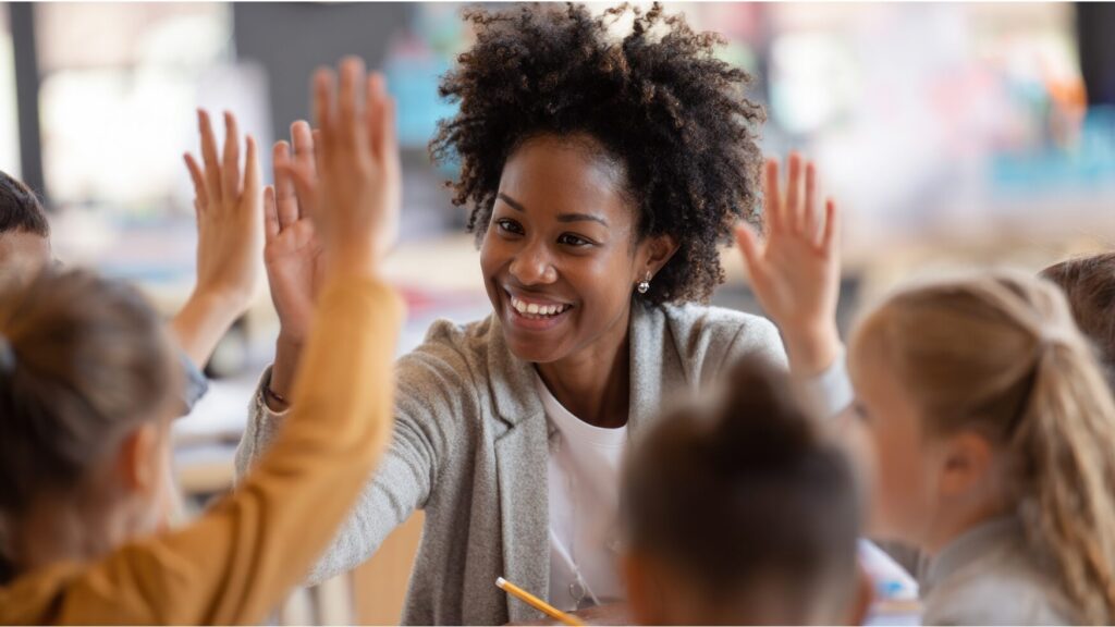 Image of a teacher giving high-fives to her students.