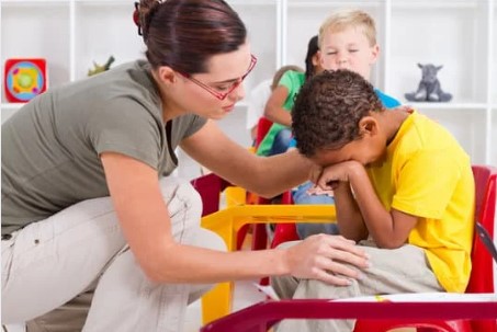 A female teacher comforts a crying child