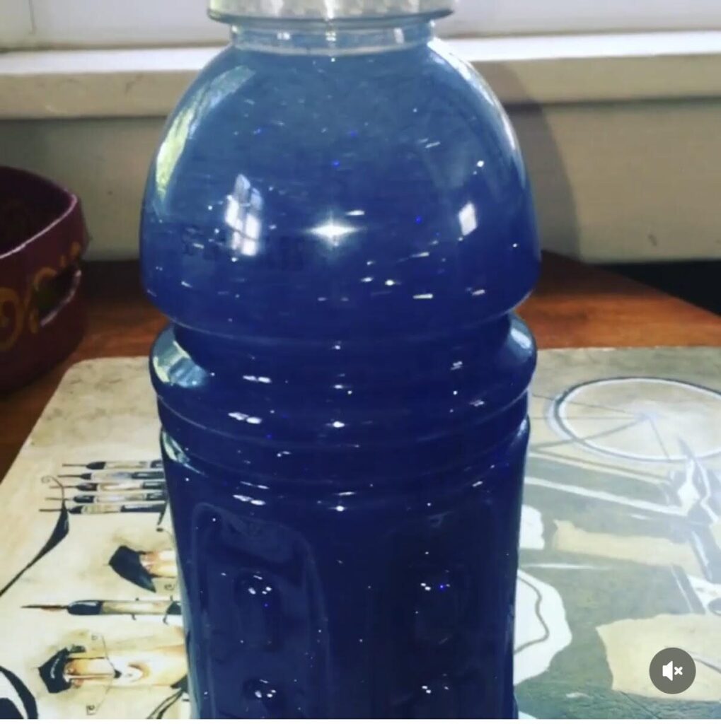 Blue sensory bottle filled with water, glue, and glitter 