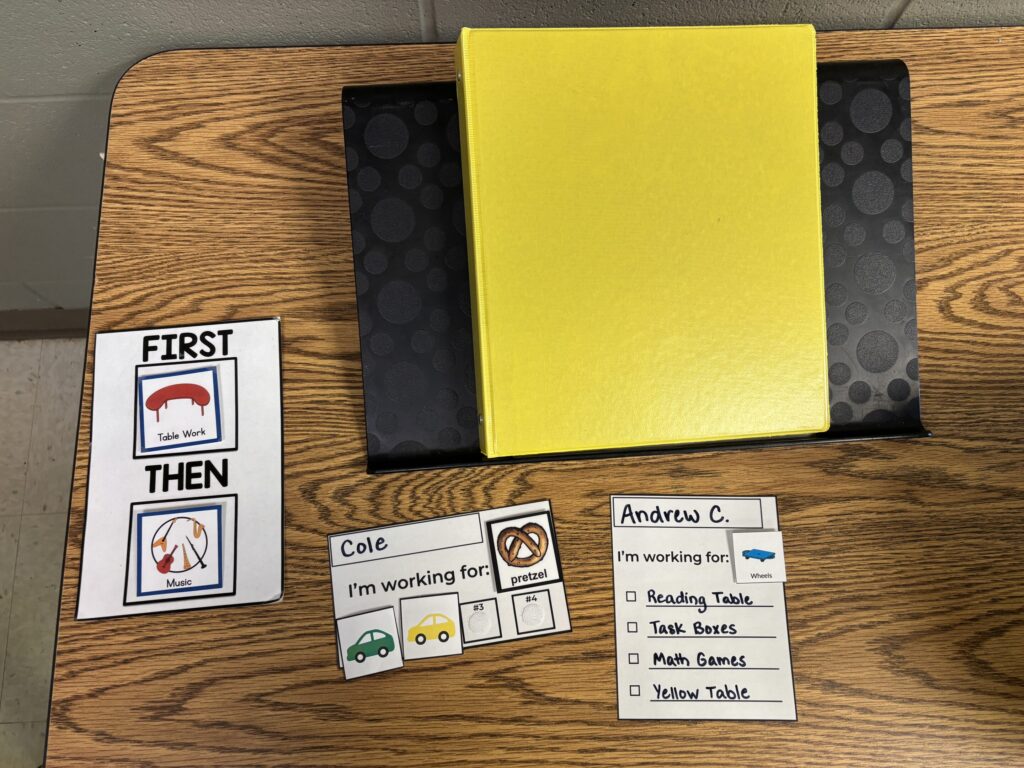 A first/then board sits on a table with a binder as well as centers visuals and a checklist of centers