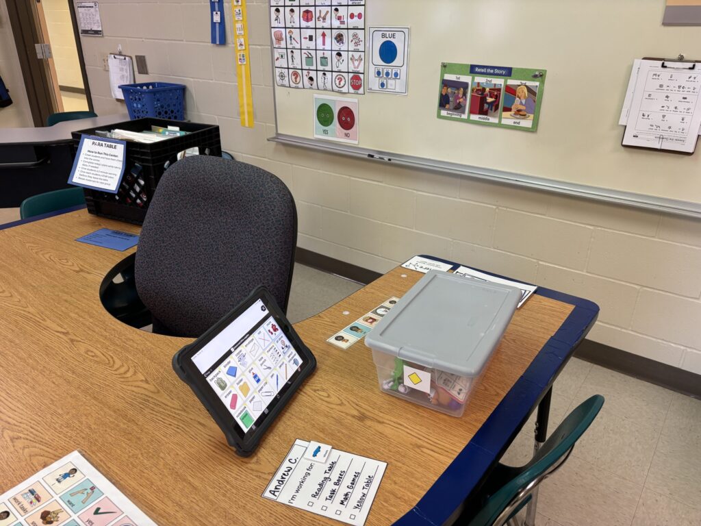 A U shaped table stands near a whiteboard for group work. Differentiation is done within group work as a communication device is shown next to a task box.