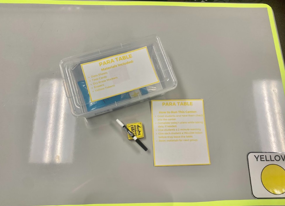 A classroom table with a bin labeled "para table." The bin has directions for the center.