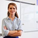A female teacher standing in front of a classroom whiteboard