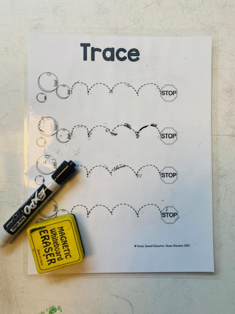 A laminated tracing worksheet is shown  on a table with a dry erase marker and eraser