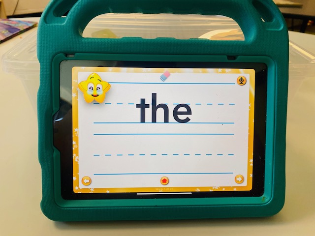 An iPad is shown on a table. A sight word game is on the screen.
