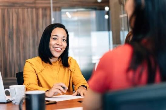 Woman sitting at a desk smiling at a woman sitting across from her