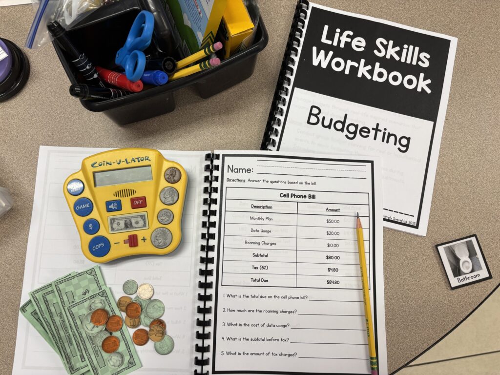 Budgeting and reading bills workbooks lay on a table top with a visual coin-u-lator calculator and pretend money