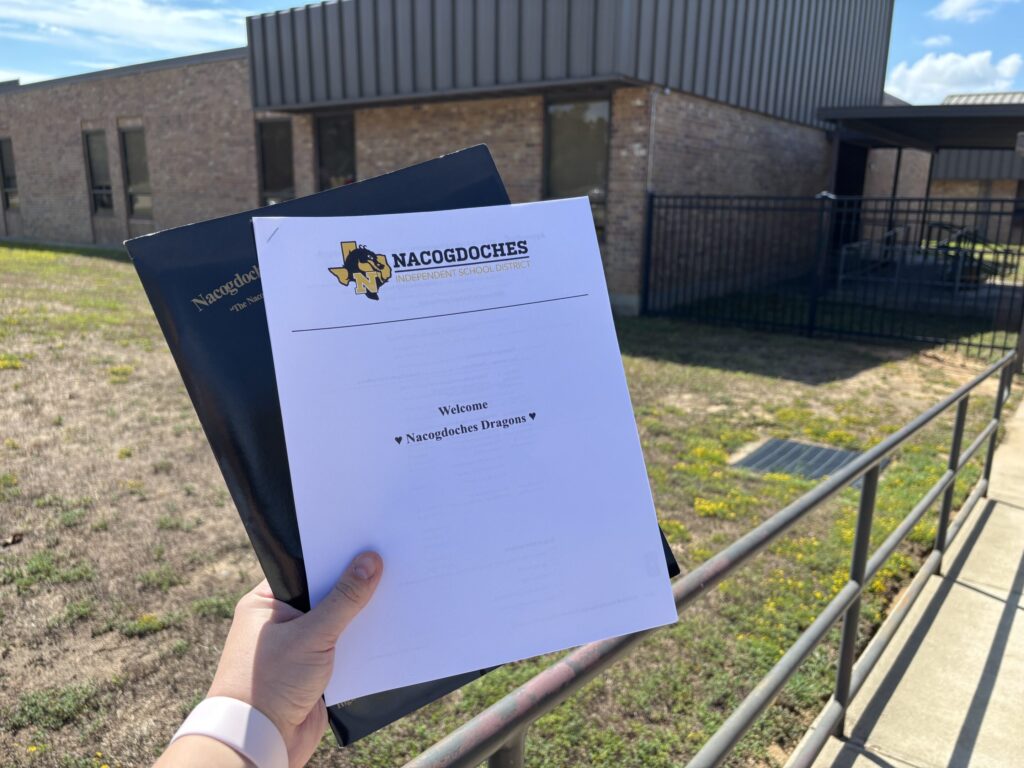 A welcome letter is held up in front of a school building
