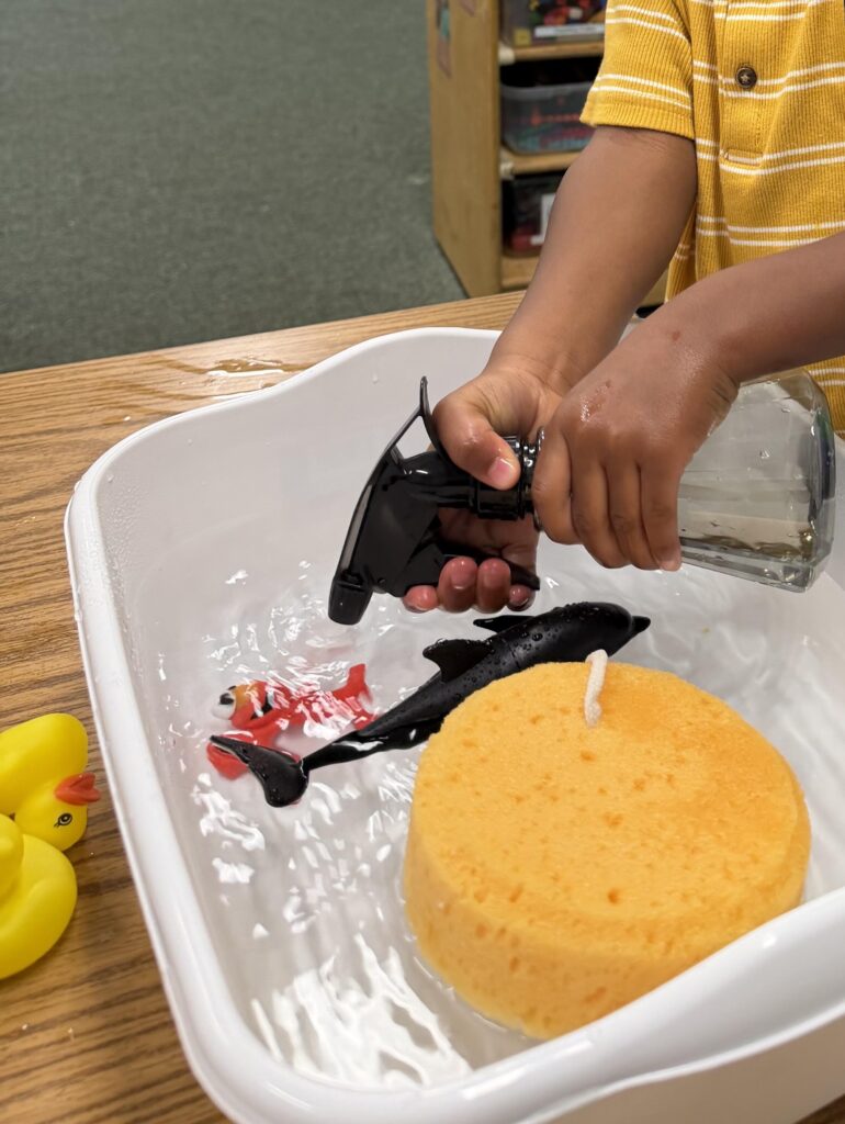 A student playing in a bucket of water with water toys