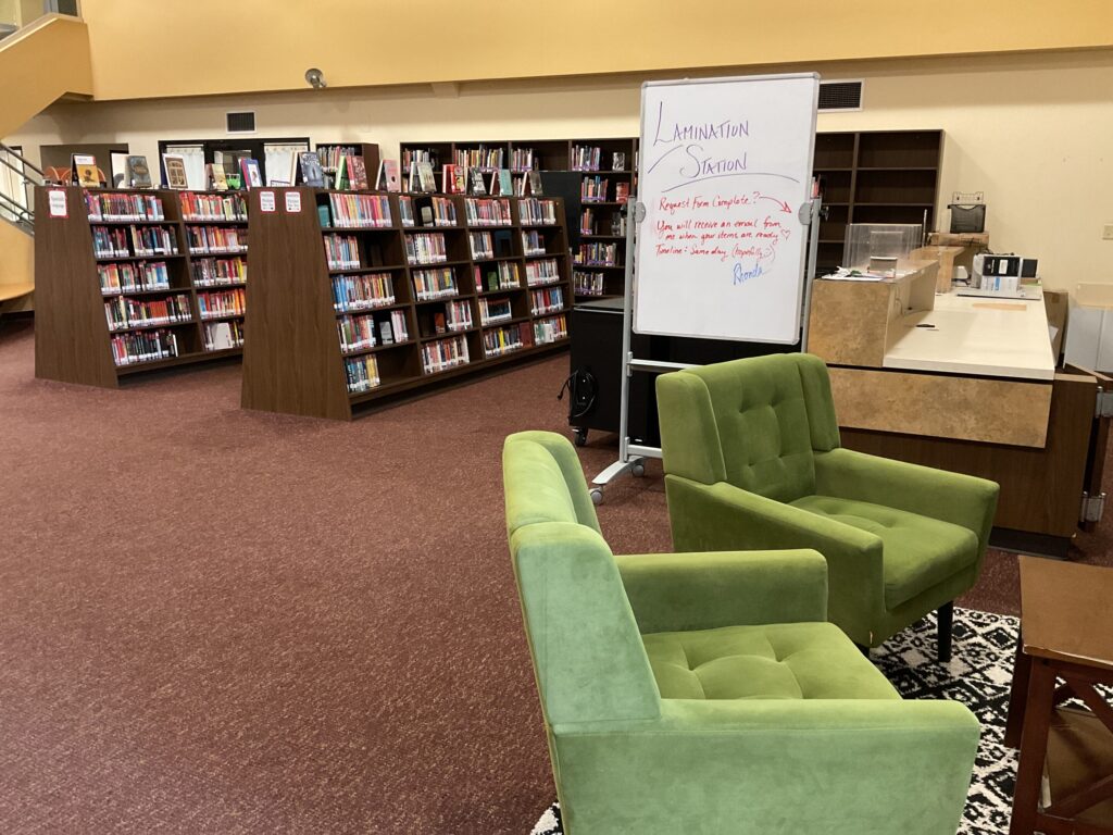 Library shelves are shown next to a teacher “lamination station” that is an available resource for teachers in the school’s library.