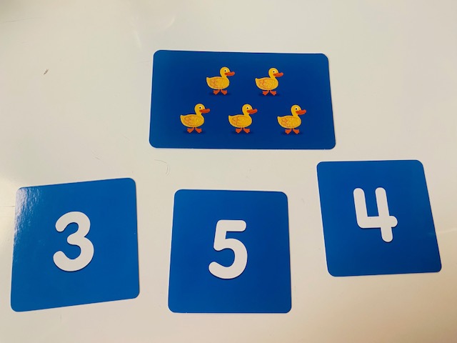 blue math cards on a table - one card has five ducks, adn there are number cards below it
