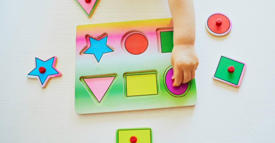 a child doing a colorful shape puzzle