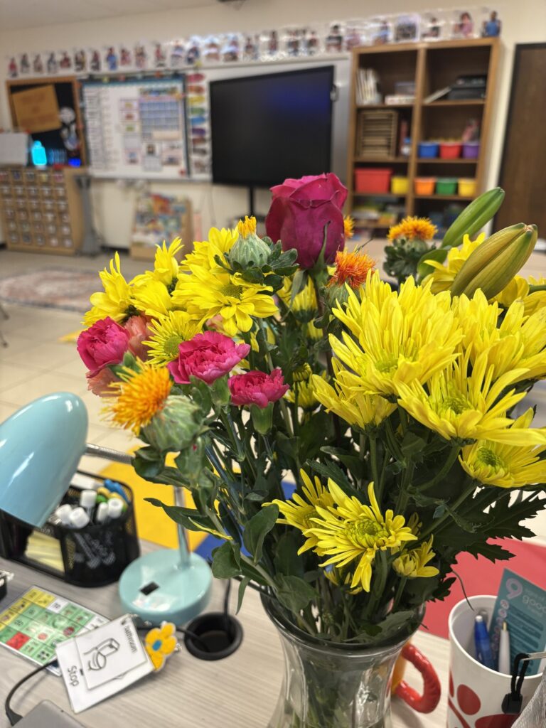 Flowers sit on a teacher desk in a classroom
