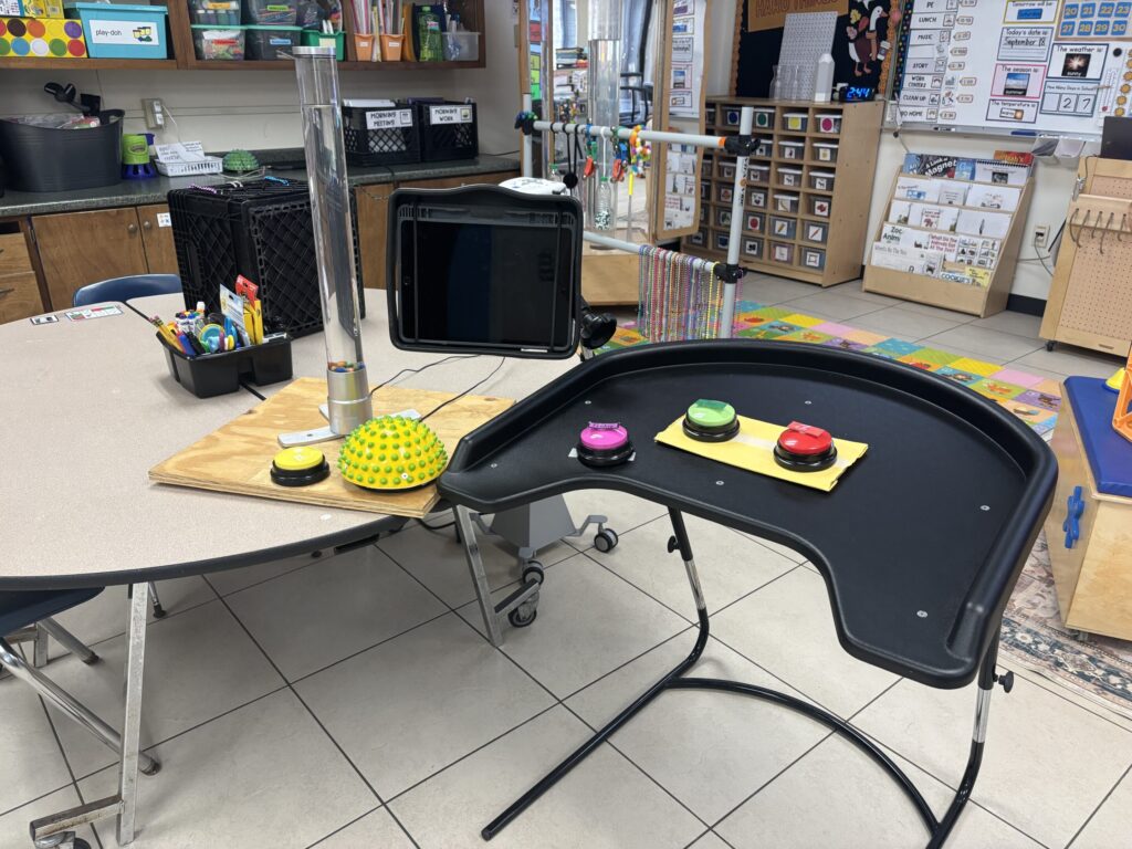 A round table is paired with a single desk that is titled for wheelchair use. 