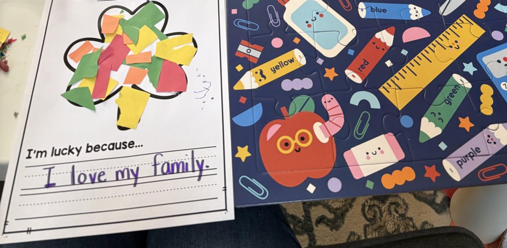 Image showing a four leaf clover craft that says "I am lucky because I love my family" next to a puzzle with school supplies on it.