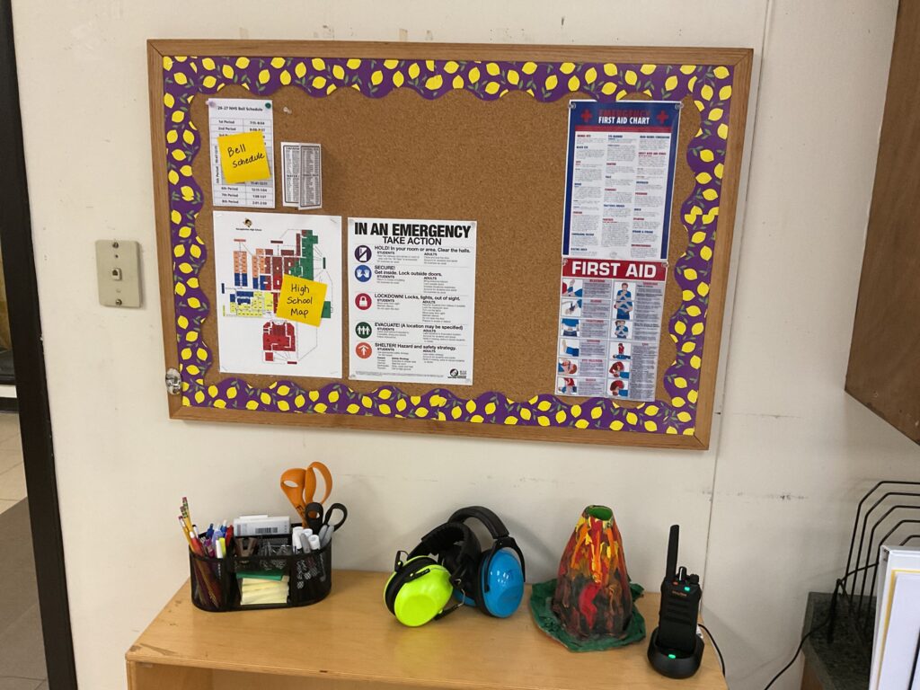A bulletin board has a schoo map along with other helpful postings like emergency information and first aid.